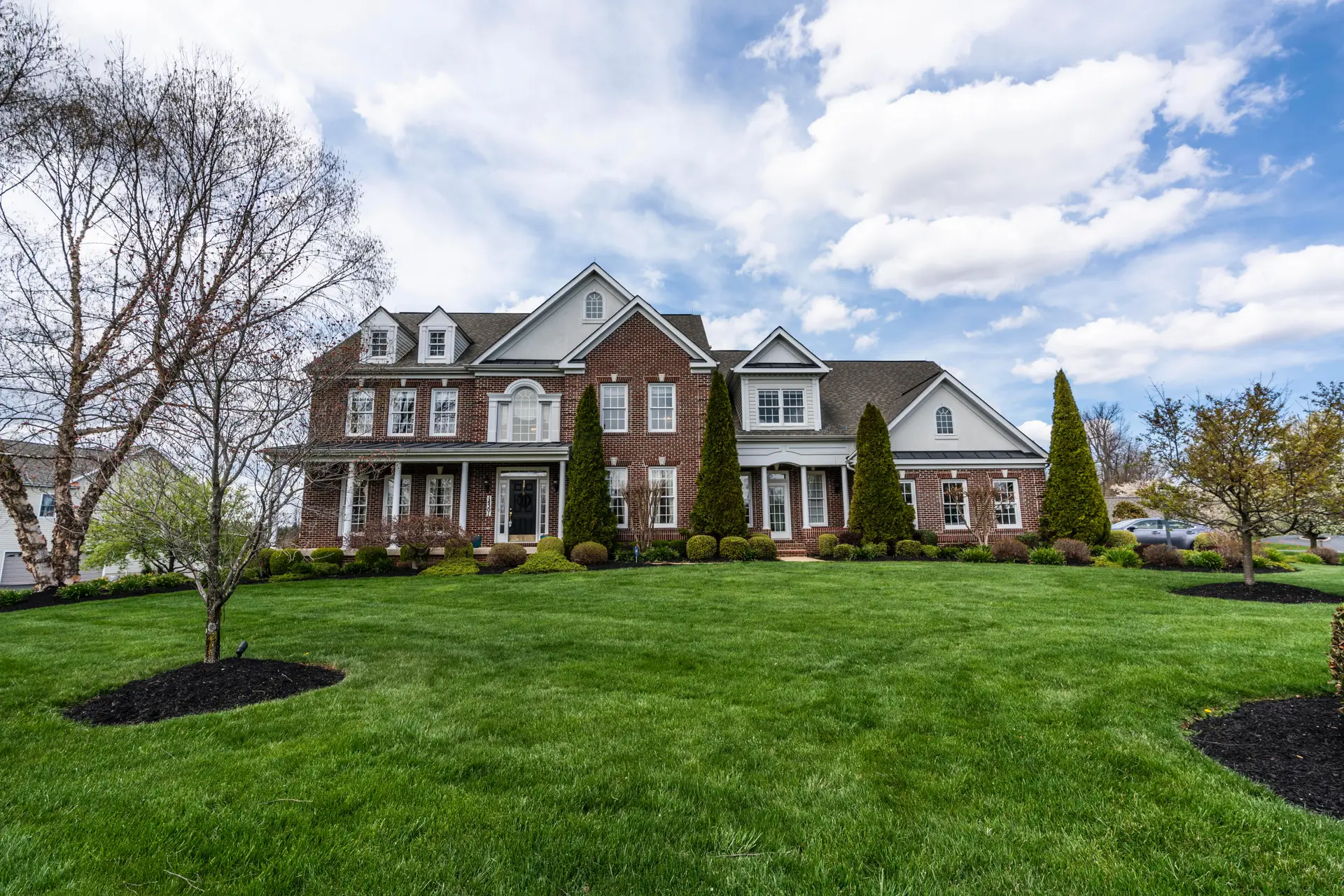 two-story brick home with grassy front yard