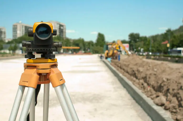 professional land survey equipment in front of new construction site